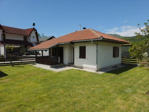a small white house with a grass yard at Apartmani LUX in Kolašin