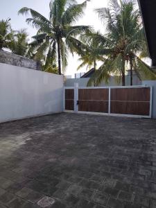 a patio with palm trees and a white fence at Sonne Villa in Pangandaran