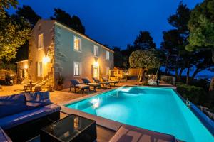 a swimming pool in front of a house at night at Holiday house Pantovčak, secluded stone house without other guests,with heated pool and unique view in Rab