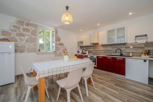 a kitchen with a table and chairs in a kitchen at Holiday house Pantovčak, secluded stone house without other guests,with heated pool and unique view in Rab