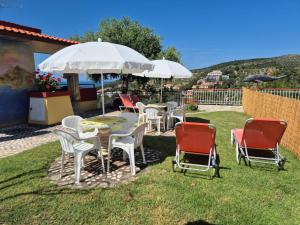 a group of chairs and tables under an umbrella at Sunset Apartments & Studios in Limenaria