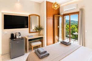 ein Schlafzimmer mit Bett, Fernseher und Fenster in der Unterkunft Artemida Pansion Georgioupolis in Kournás