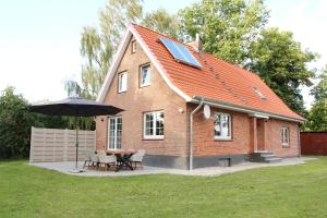 a house with an umbrella and a table and chairs at Hof Muhs in Stakendorf