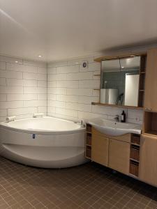 a large white bathroom with a tub and a sink at Mysigt litet hus in Näsum
