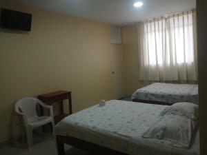 a small bedroom with two beds and a chair at Hospedaje San Valentin in Capitan Concha