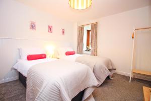two beds in a room with white sheets at Attractive barn conversion near Padstow in Saint Merryn