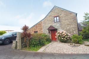 a brick house with a red door and a car at Attractive barn conversion near Padstow in Saint Merryn