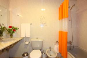 an orange shower curtain in a bathroom with a toilet at Canico Bay Apartments in Caniço