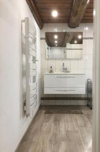 a white bathroom with a sink and a mirror at Gîte de la Buissonniere in Grand-Failly