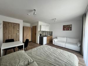 a bedroom with a bed and a desk and a kitchen at Diament Apartamenty in Rowy