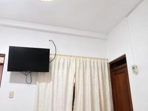 a flat screen tv hanging on a wall next to a window at Hospedaje Triton in Máncora