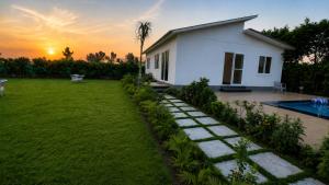 a house with a garden and a swimming pool at Vijay Laxmi Farm House in Manjhāoli