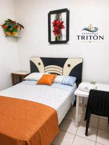 a bedroom with a bed with an orange blanket and a table at Hospedaje Triton in Máncora