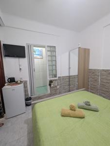 a bedroom with a green bed with two towels on it at Angel Room 1 in Nea Plagia