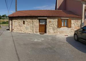 a small stone house with a brown door and a car at El Lagar de Mailusa in Sayar