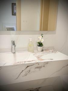a bathroom sink with a mirror and a vase of flowers at شقق واحة المحمدية in Baljurashi +27 photos