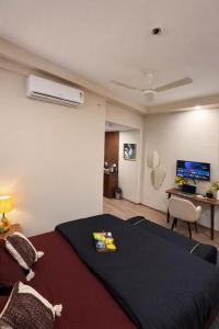 a bedroom with a bed and a desk with a tv at Sunbliss Corner in Greater Noida
