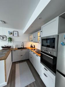 a kitchen with white cabinets and stainless steel appliances at Puffin rock in Vestmannaeyjar