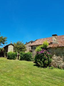 an old stone house with flowers in a yard at Casa Gasamáns in Amés