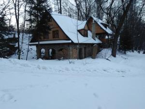 a house with a snow covered roof in the snow at Apartmán Belko in Hrádek