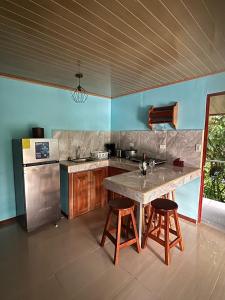 a kitchen with a large table and two bar stools at La Reina del Mar in Drake