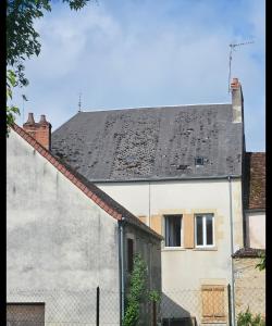 a white house with a black roof and a fence at Church View Apartments in Châteauneuf-Val-de-Bargis