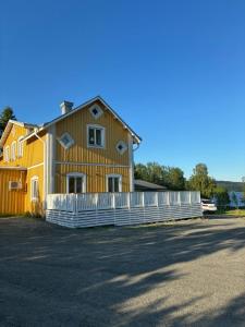 a yellow house with a white fence in front of it at Strandvillan in Älandsbro
