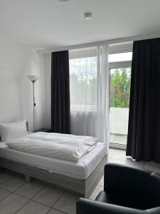 a bedroom with a bed and a chair and a window at Hotel Main Taunus in Hochheim am Main