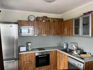 a kitchen with wooden cabinets and a stainless steel refrigerator at Вила Арапя in Tsarevo +76 photos
