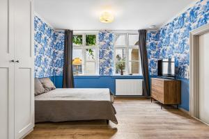 a bedroom with blue walls and a bed and a television at Det gamle Apotek Møn in Stege