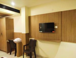 a room with a tv on a wall with chairs at Hotel Royal Stay in Madurai