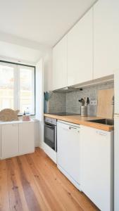 a kitchen with white cabinets and a wooden floor at Apartamentos Aurea - Sesimbra in Sesimbra