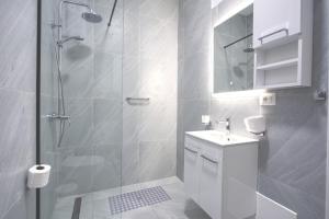 a white bathroom with a shower and a sink at Southern Nights in Gjilek