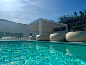 a swimming pool with lounge chairs in front of a building at Fenici Levanzo Hotel - Adults Only in Levanzo