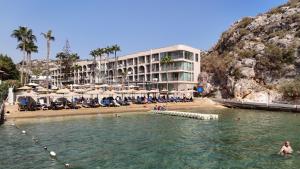 a hotel on a beach with people in the water at Altınorfoz Hotel in Ayaştürkmenli