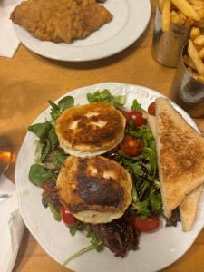 two plates of food with sandwiches and a salad at Eötvös Hotel in Ajka