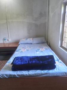 a bed in a room with a blue blanket on it at Gobrela homestay in Bardiyā