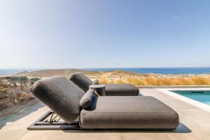 two lounge chairs sitting on a patio next to a swimming pool at Tinos Prinos 3 in Agios Fokas