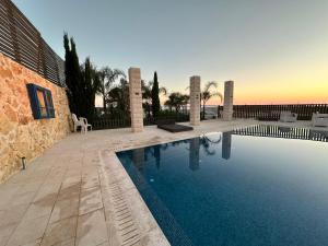 a swimming pool in front of a building with a sunset at carmel cabins suite 12 in Yājur