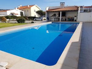 una piscina azul frente a una casa en O Paraíso no Terraço, en Foz do Arelho