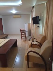 ein Wohnzimmer mit Sofa, Sesseln und Fernseher in der Unterkunft Serrano Park Hotel in Parauapebas