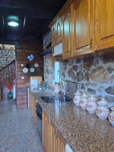 a kitchen with wooden cabinets and a stone wall at Casa Nardo in Benia de Onís +7 photos