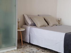 a bed with white sheets and pillows next to a table at Campello Muchavista Beach in El Campello