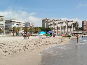 a group of people on a beach with buildings at Campello Muchavista Beach in El Campello
