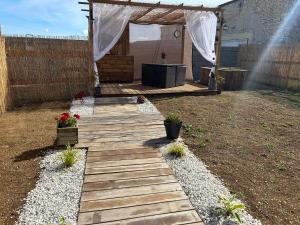 a wooden pathway leading to a backyard with a gazebo at La maison du bonheur 17 in Marans