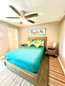 a bedroom with a blue bed with a ceiling fan at Wake up 2 Quiet Ocean Views, centrally located A1A in Ormond Beach