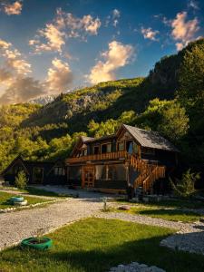 a large wooden house with a mountain in the background at Thethi Villas in Theth