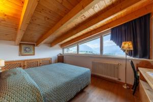a bedroom with a bed and a large window at Residenza Bagni & Miramonti in Cavalese