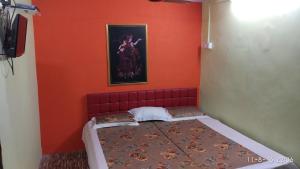 Habitación pequeña con cama con pared de color naranja en Radha Krishna Home, en Varanasi