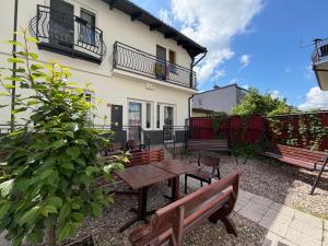 a patio with benches and a table in front of a house at Pokoje Gościnne & Apartamenty Przemyk in Rewa